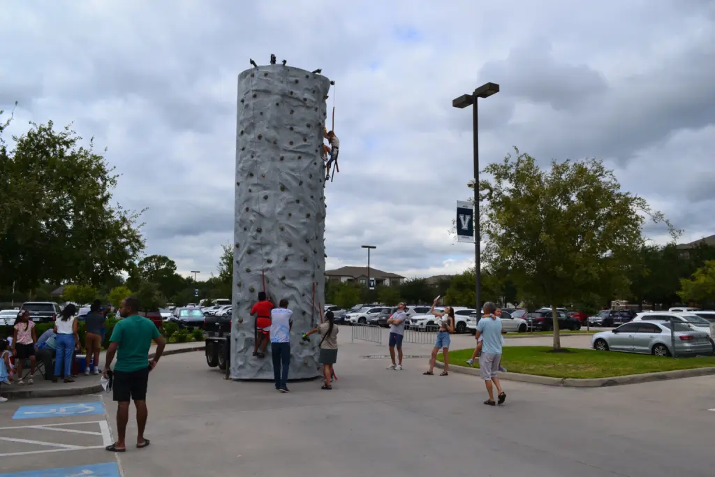 Kids climbing tall inflatable rock wall at outdoor event
