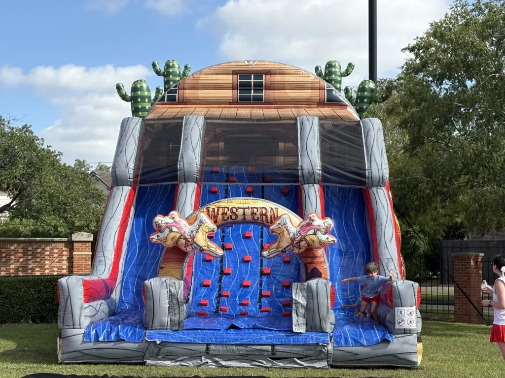 Boy climbing Western-themed inflatable slide with cacti