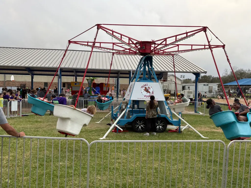 Kids riding Texas Round Up spinning gondola carnival ride