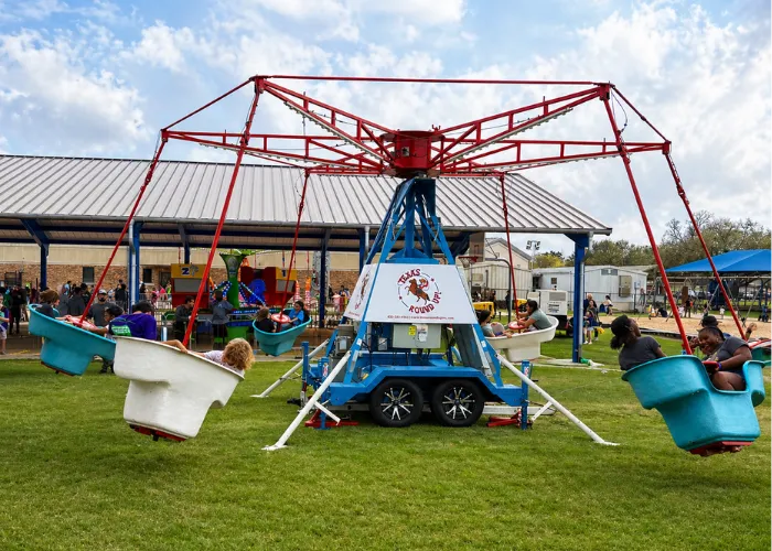 Kids riding Texas Round Up spinning gondola ride outdoors